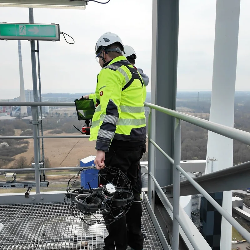 drohnenpilot und kunde stehen auf kesselhaus