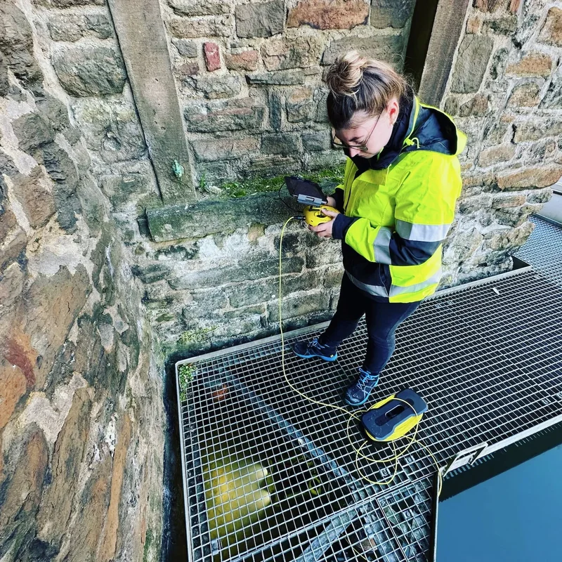 Pilotin mit Unterwasserdrohne bei Kläranlagen-Inspektion